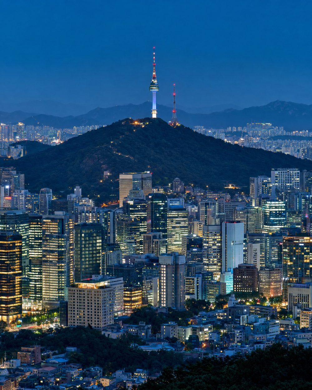 The Seoul skyline at dusk with the mountains and N Seoul Tower behind the city